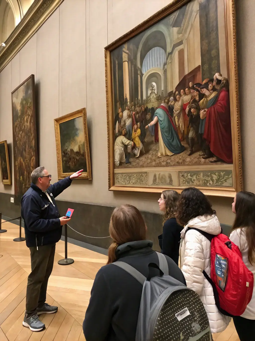 A photograph of a docent leading a guided tour through MUSEE GORSLINE, with visitors attentively listening and observing the artwork on display.